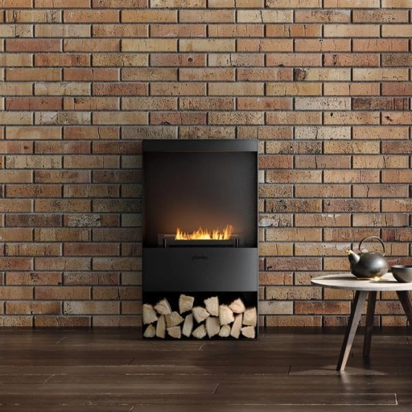 Semineu cu bioetanol Senso Stove in fata unui perete de caramida decorativa, cu flacara aprinsa.